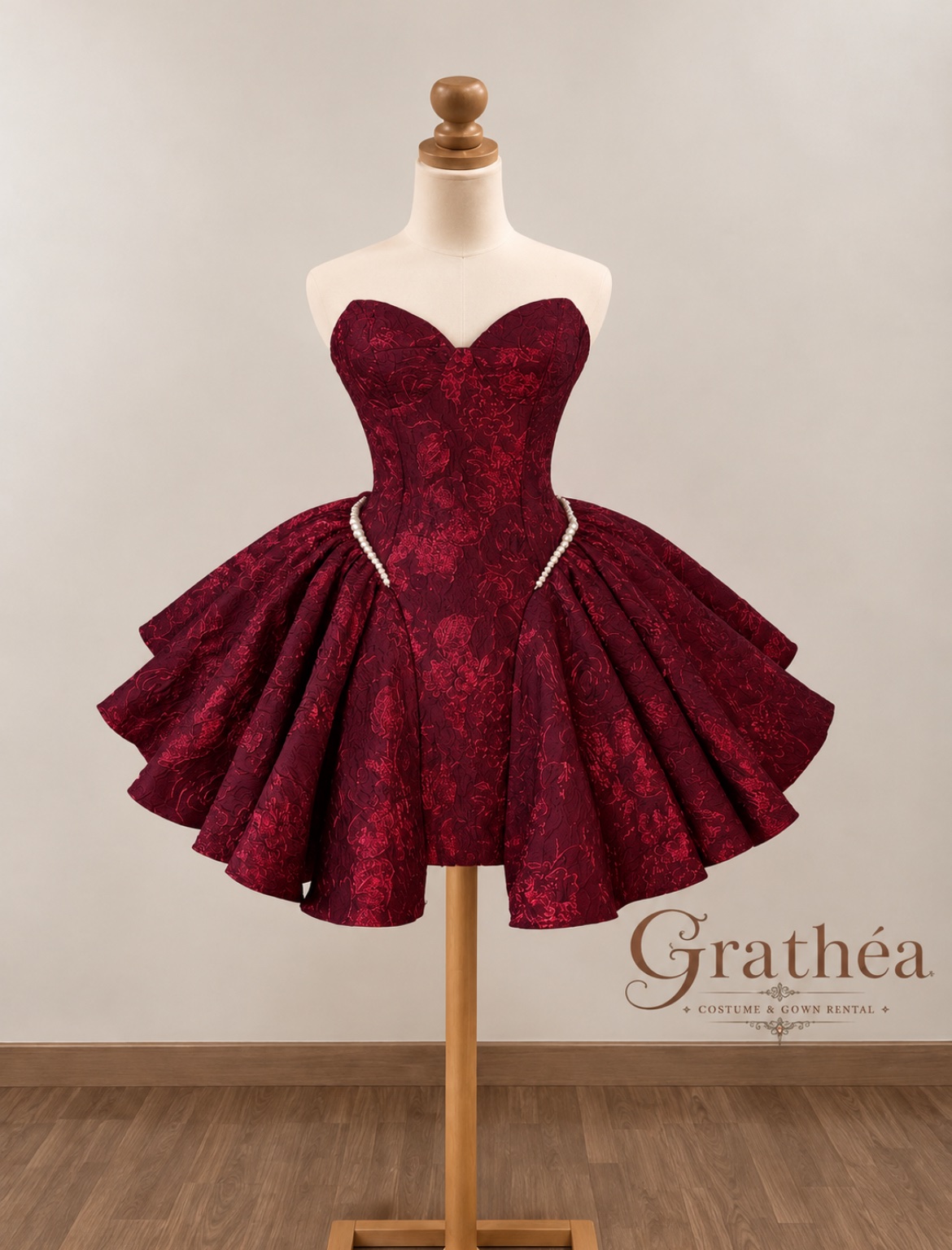 Noelle: A rich burgundy cocktail dress featuring a strapless sweetheart neckline, a structured corset-style bodice, and intricate floral textures. Pearl accents trace the hips, while a dramatic, full skirt with sculpted folds creates a romantic silhouette—elegant, bold, and beautifully regal. ❤️
